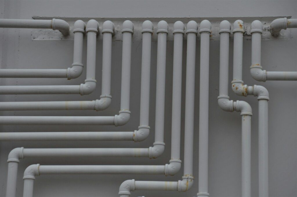 A close up of pipes on a wall that need professional leak detection.