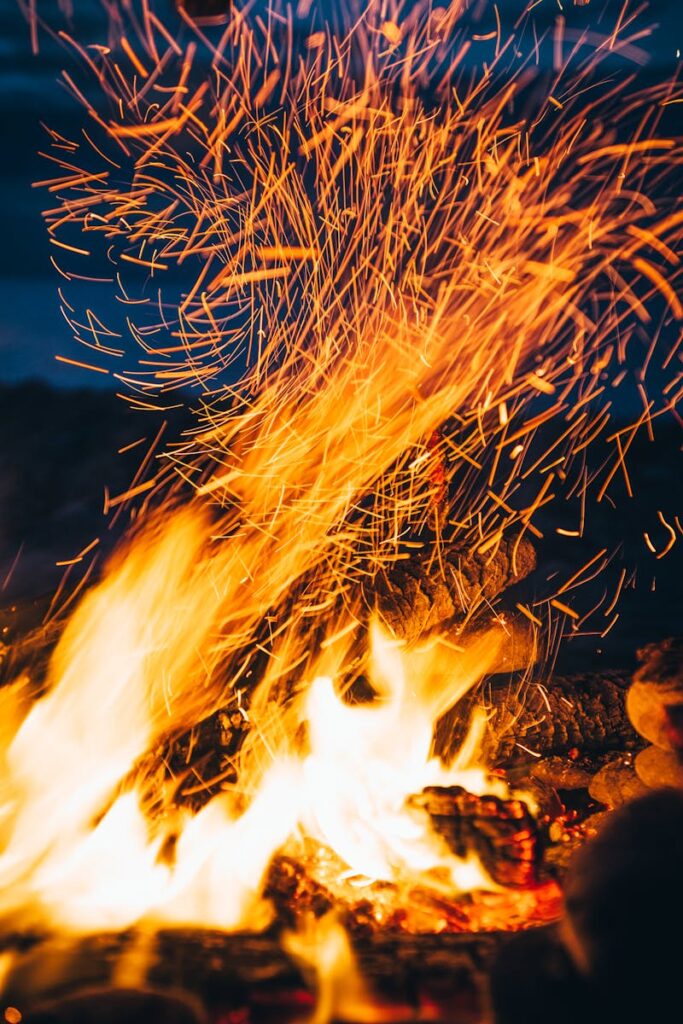 Close-up of a campfire with sparks flying in a vibrant outdoor setting at night. How could wildfire impact indoor air quality?